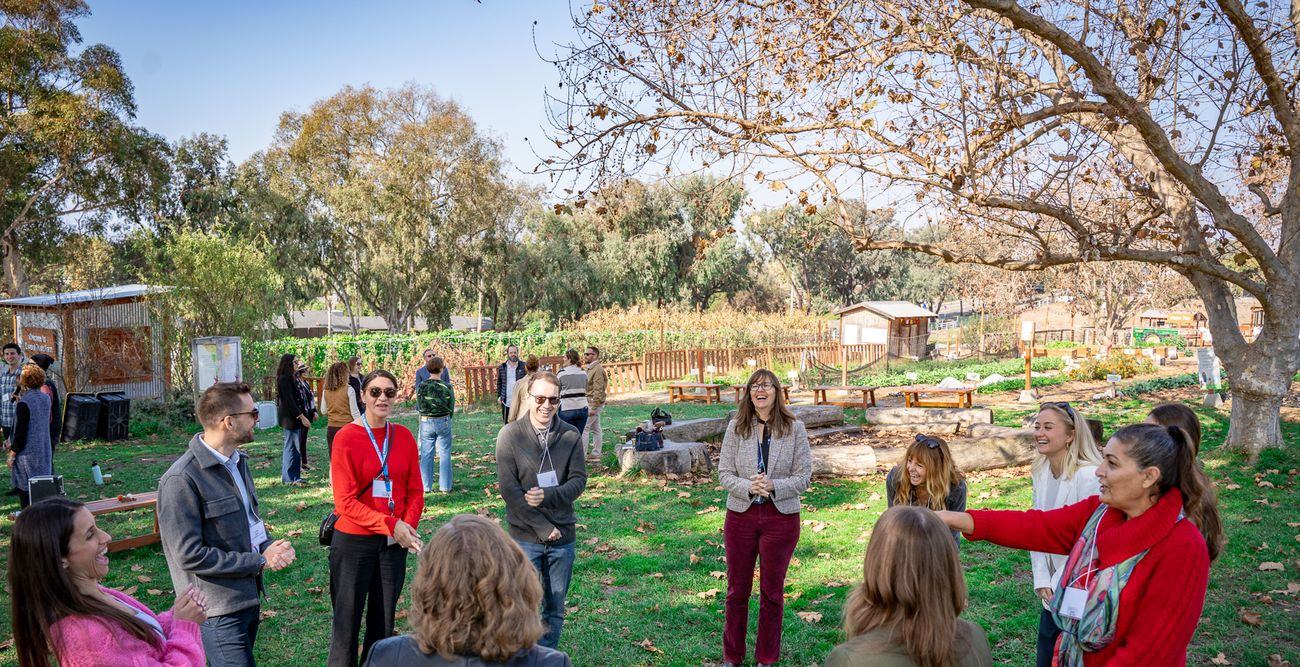 JPro colleagues gathered in a circle on the lawn during a morning program