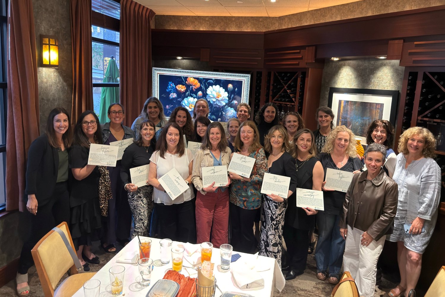 Cohort 4 of the Pauline Foster Women's Leadership Institute at their graduation dinner, holding their personal leadership statements
