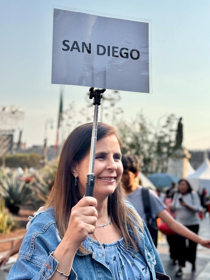 A cohort member holding the San Diego group sign during a program immersion