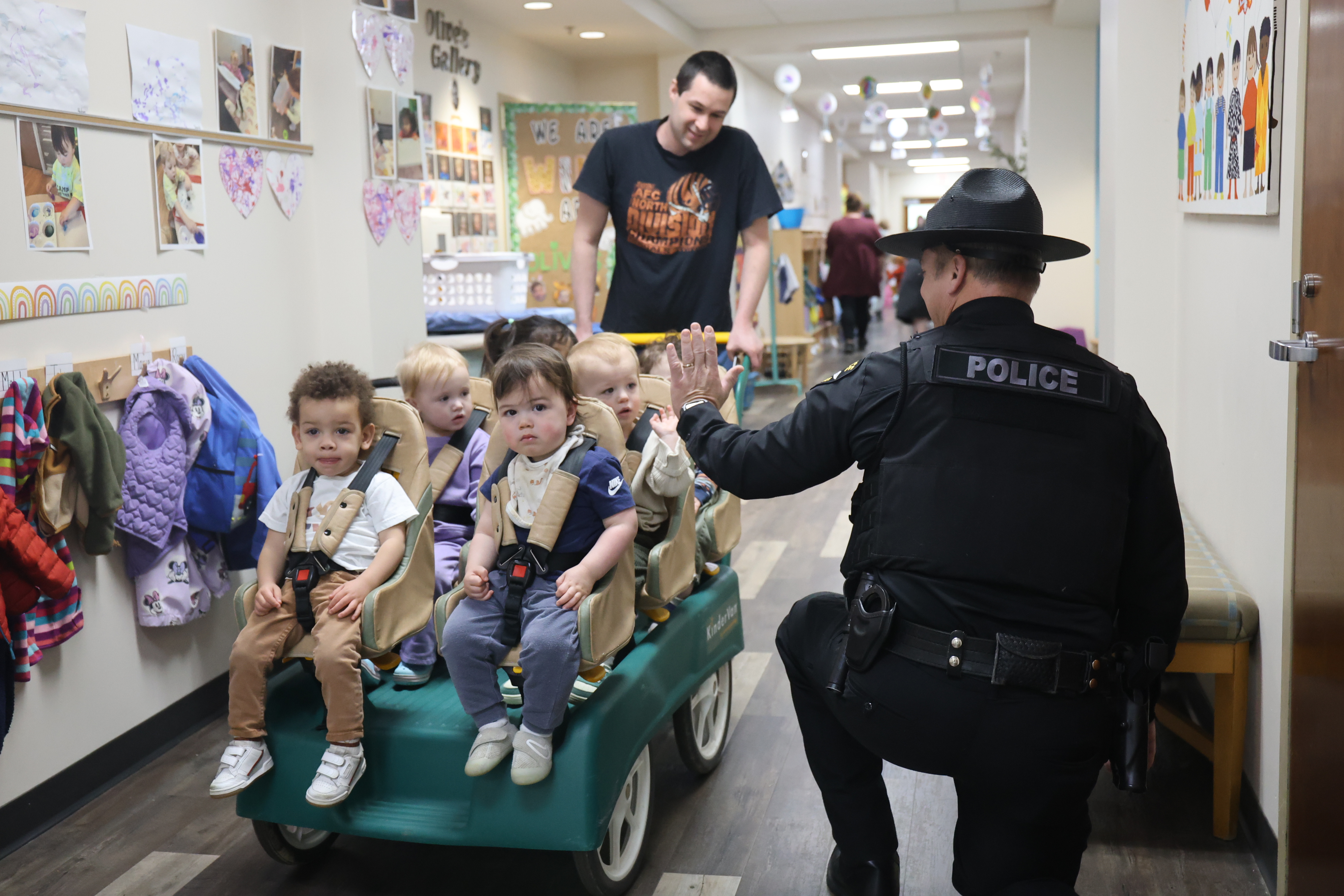 a police security officer gives high five the young Jewish preschool students